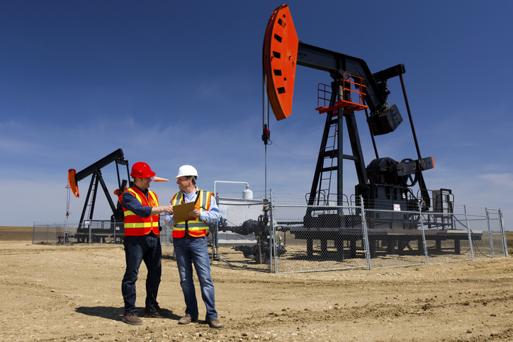 An image of two oil workers at a pumpjack.